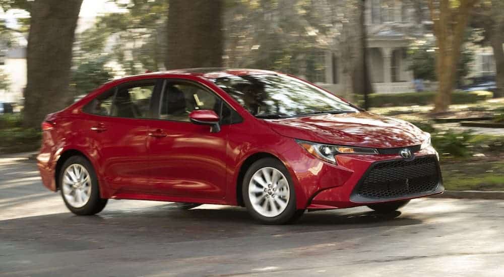 A red 2020 Toyota Corolla is driving through a residential area. 