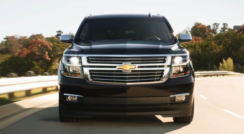 A black 2020 Chevy Suburban is shown from the front while driving down a highway.