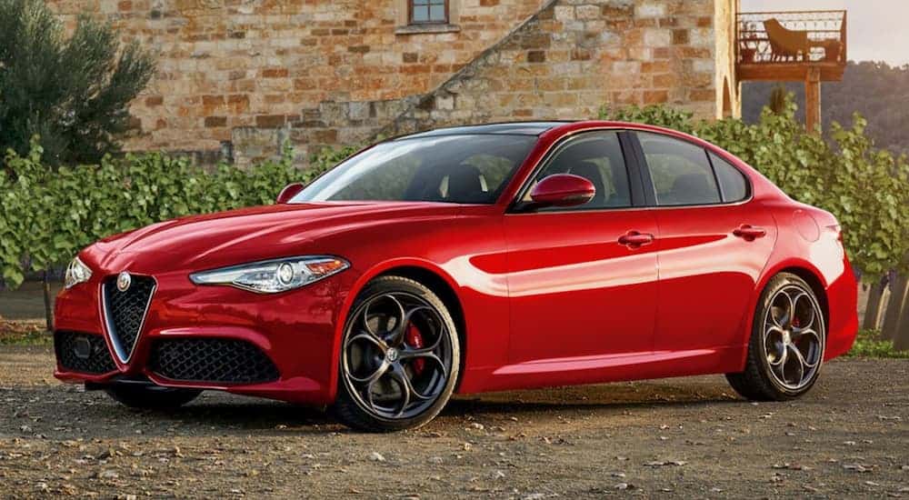 A 2019 red Alfa Romeo Giulia is parked in front of a brick building.
