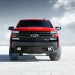 The front end of a 2020 red Chevy Silverado 1500 is parked on white sand.