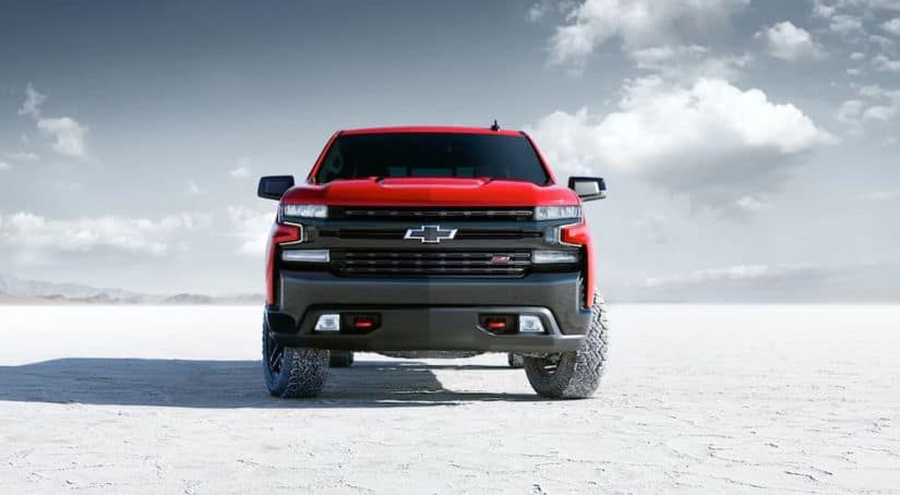 The front end of a 2020 red Chevy Silverado 1500 is parked on white sand.