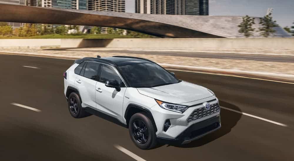 A white 2020 Toyota RAV4 is driving on a highway. 