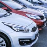 Used cars are shown in a row at a used car dealership.