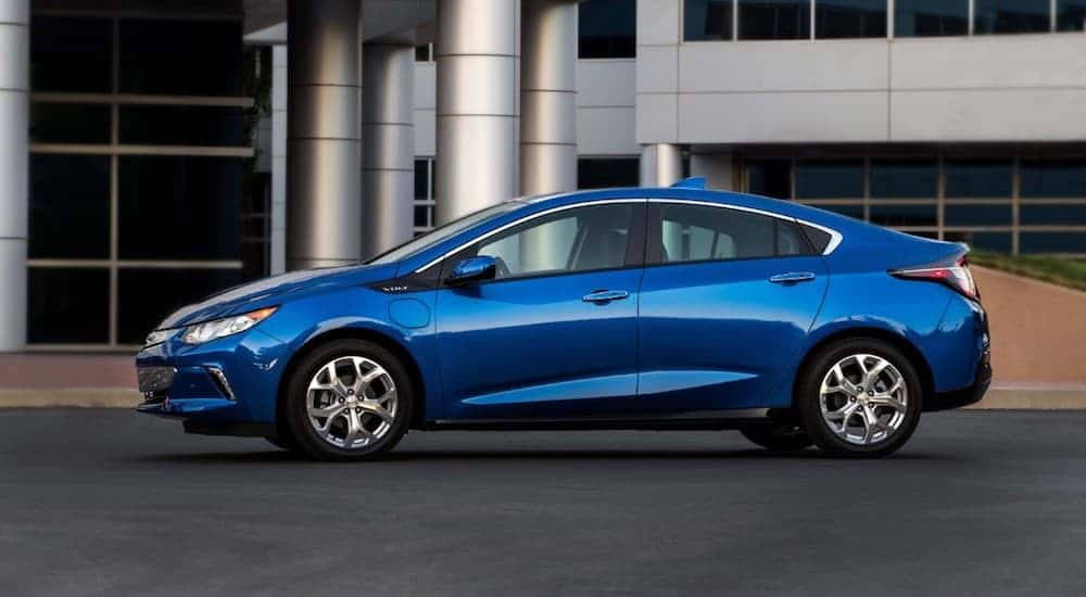 A blue 2018 Chevy Volt, a popular used car found at used car dealerships, is parked in front of a business building. 