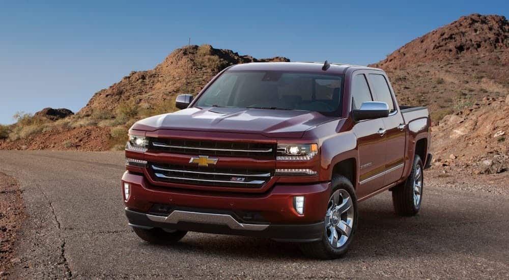 A red 2017 Chevy Silverado 1500, which is a popular option among used trucks sale, is parked on a road in the desert. 