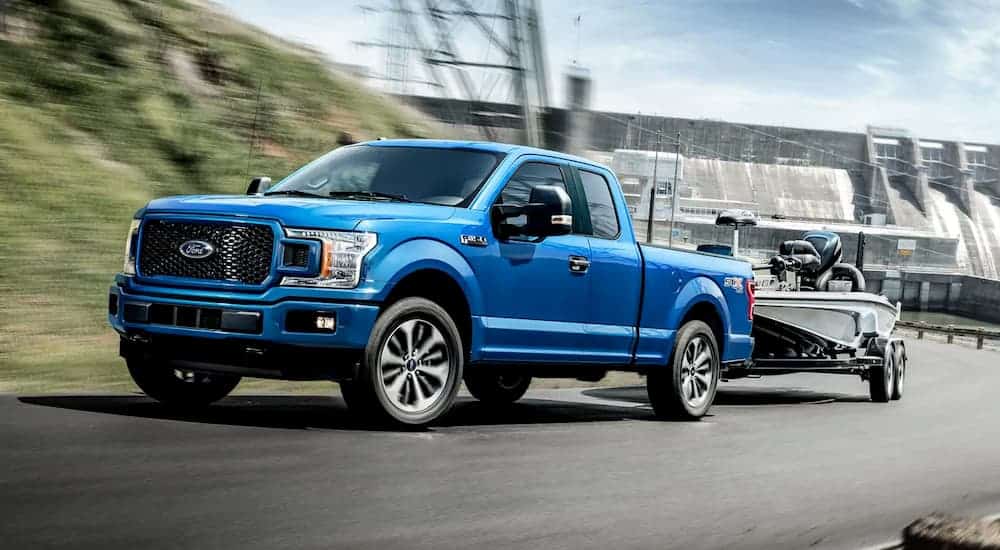 A blue 2019 Ford F-150 is towing a boat uphill.