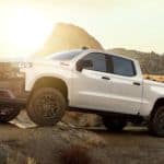 A white 2019 Chevy Silverado 1500 Custom Trail Boss is off-roading at sunset.