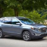A blue 2019 GMC Terrain is parked next to a treelined river side.