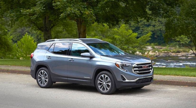 A blue 2019 GMC Terrain is parked next to a treelined river side.