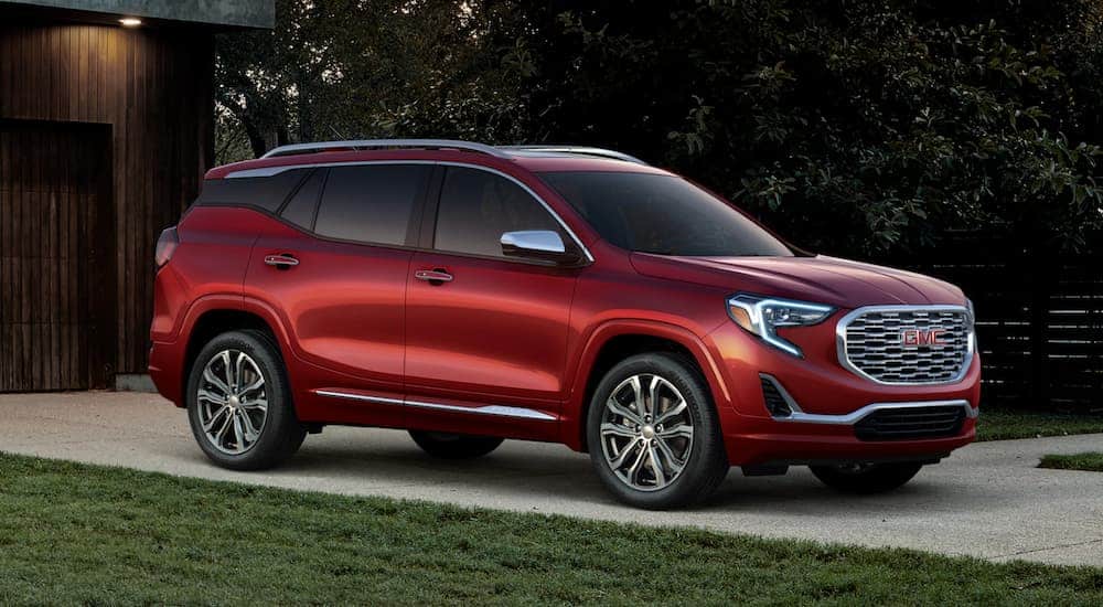A red 2019 GMC Terrain, which wins when comparing the 2019 GMC Terrain vs 2019 Mazda CX5, is parked in a driveway during dusk.