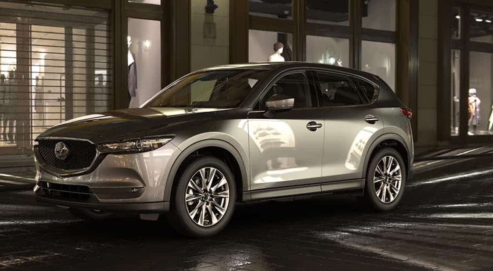 A grey 2019 Mazda CX-5 is parked on a dark city street.