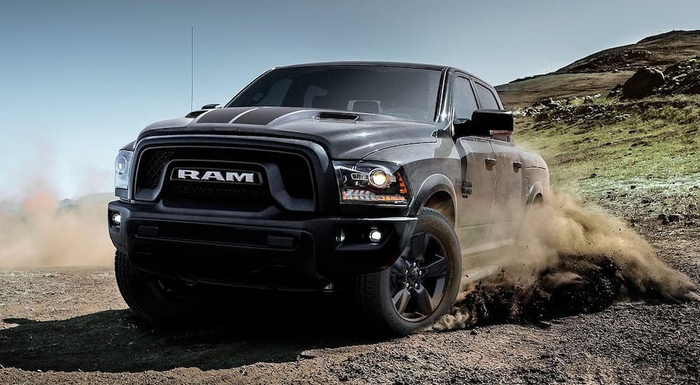 A black 2019 Ram 1500 Classic is spraying dirt while off-roading.