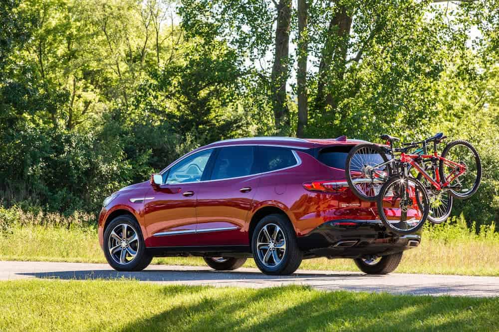 A rear look at a red 2020 Buick Enclave Avenir parked on a treelined road.