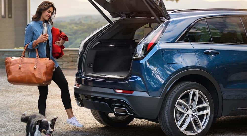 A woman is using the liftgate feature of her blue 2020 Cadillac XT4.