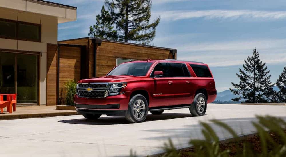 A red 2020 Chevy Suburban is parked outside of a modern house.