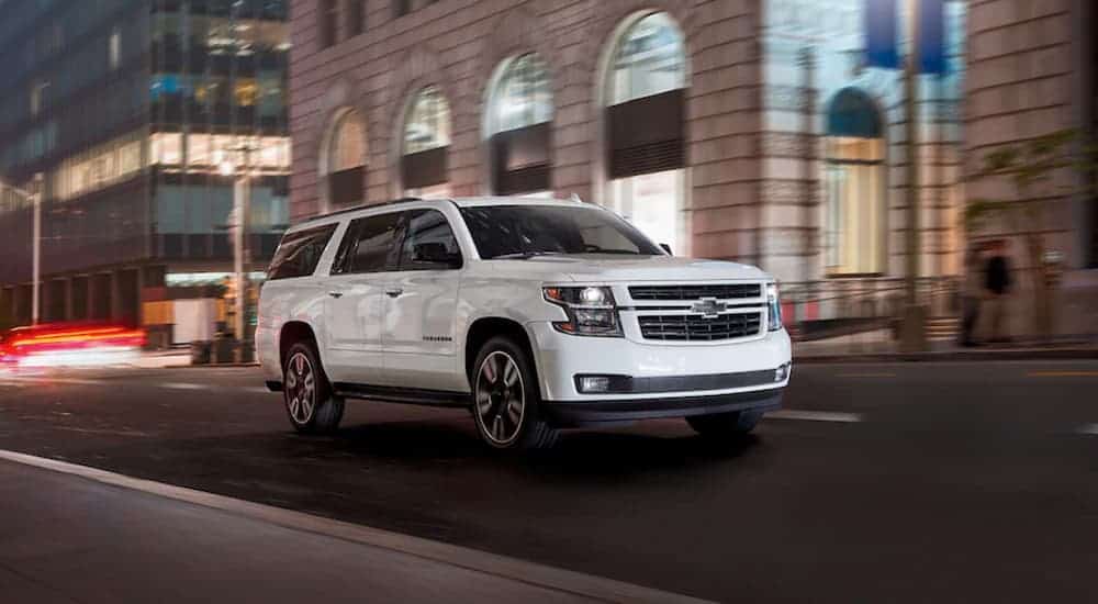 A white 2020 Chevy Suburban is driving on a city street at night.