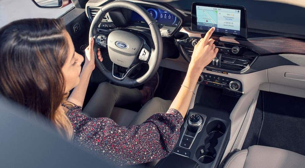A birds eye view of a woman in the drivers seat of a 2020 Ford Escape using the infotainment system. 