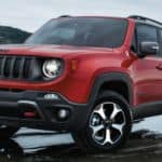 A red 2020 Jeep Renegade is driving through a large puddle.