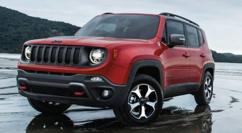 A red 2020 Jeep Renegade is driving through a large puddle.