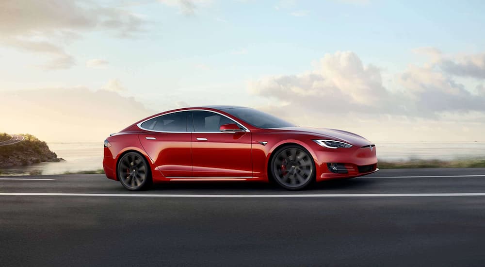 A red 2020 Tesla Model S is driving on a highway.