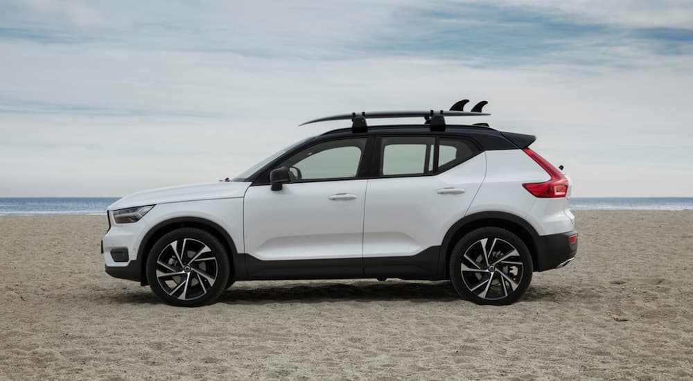 A white Volvo XC40 is parked on a beach. 