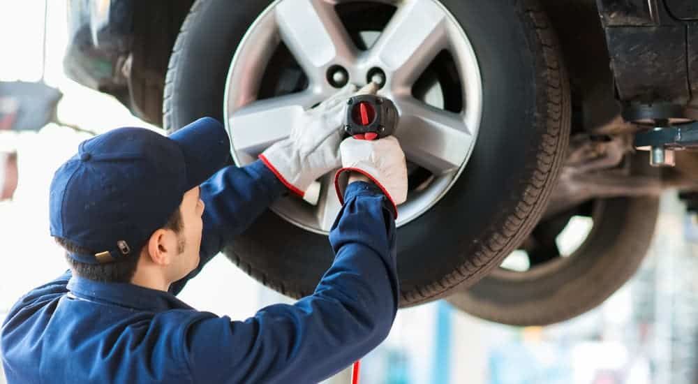 A mechanic at a local garage, similar to a garage you can find when searching, 'car service near me', is replacing a tire. 