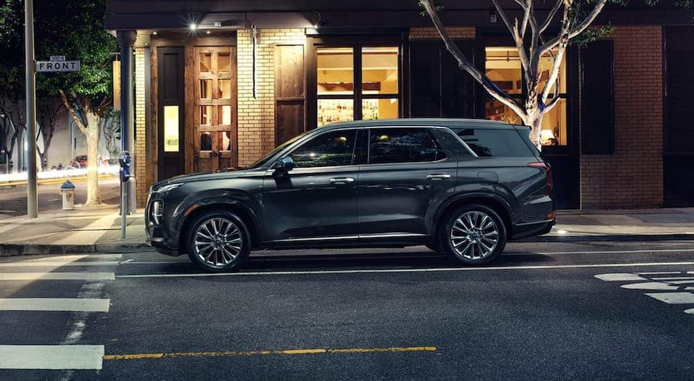 A dark grey 2020 Hyundai Palisade, popular in current auto news, is parked on a city street at night.