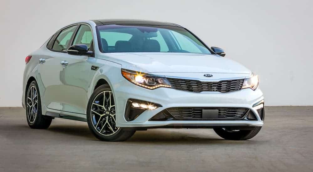 A white 2020 Kia Optima is parked in a parking lot on a foggy day.