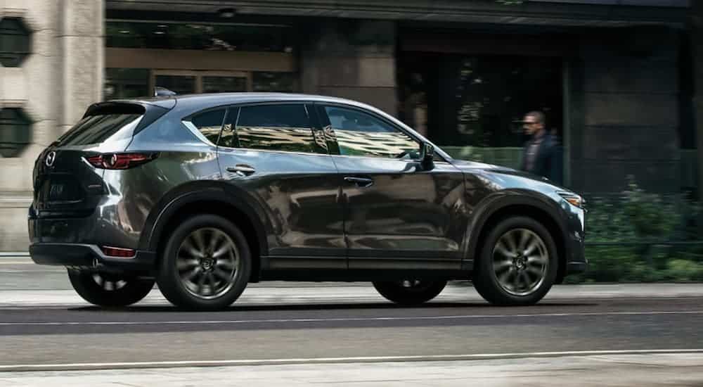 A grey 2019 Mazda CX-5 is driving down a city street. 