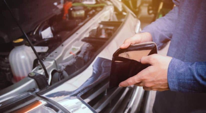 A man has his wallet open ready to pay for repairs on his used car.