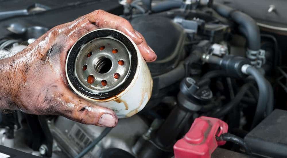 A man is doing an oil change, which is one of the most important tasks to do on used cars, on his used car. 