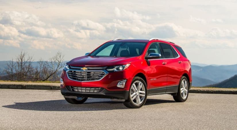 A red 2020 Chevy Equinox is parked in an empty parking lot that's over looking a city.