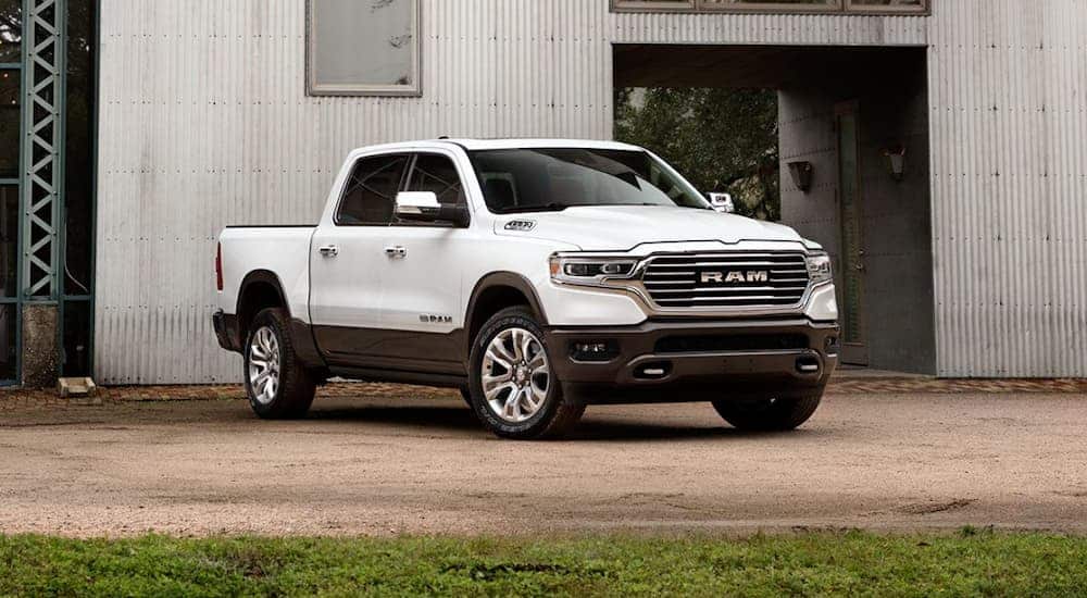 A white 2020 Ram 1500 is parked in front of a corrugated metal building.