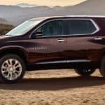 A burgundy 2020 Chevy Traverse is parked on sand with mountains in the background.