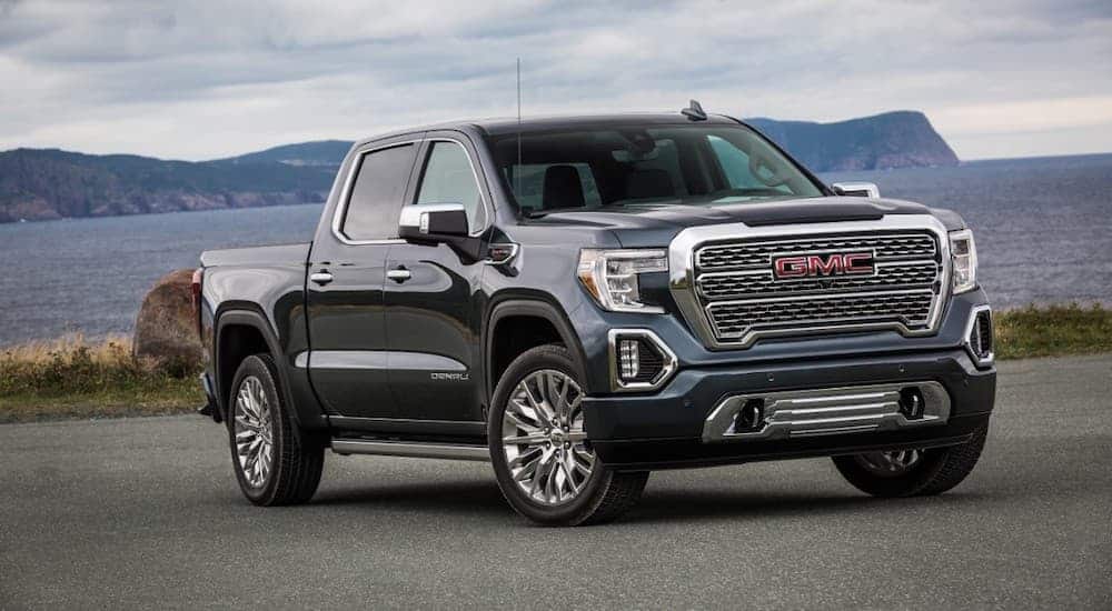 A charcoal 2020 GMC Sierra 1500 is parked with a bay and hills in the distance.