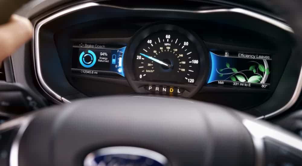Hands are on the steering wheel of a 2020 Ford Fusion showing the drivers display screen.
