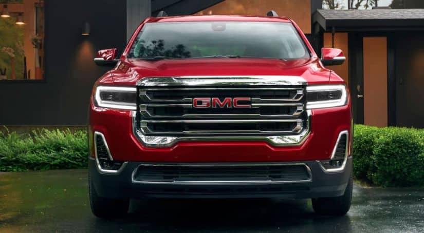 A red 2020 GMC Acadia is parked facing forward in a driveway.