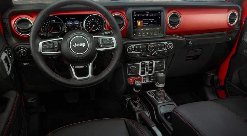 The black and red interior of a 2020 Jeep Gladiator is shown with an infotainment system.