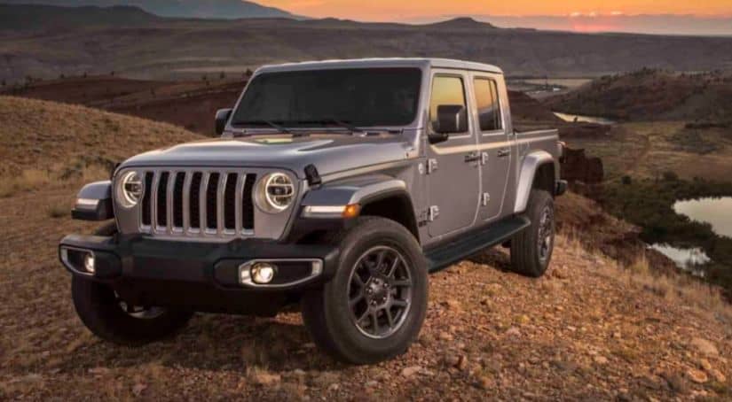 A 2020 silver Jeep Gladiator is parked on a dirt hill overlooking a valley.