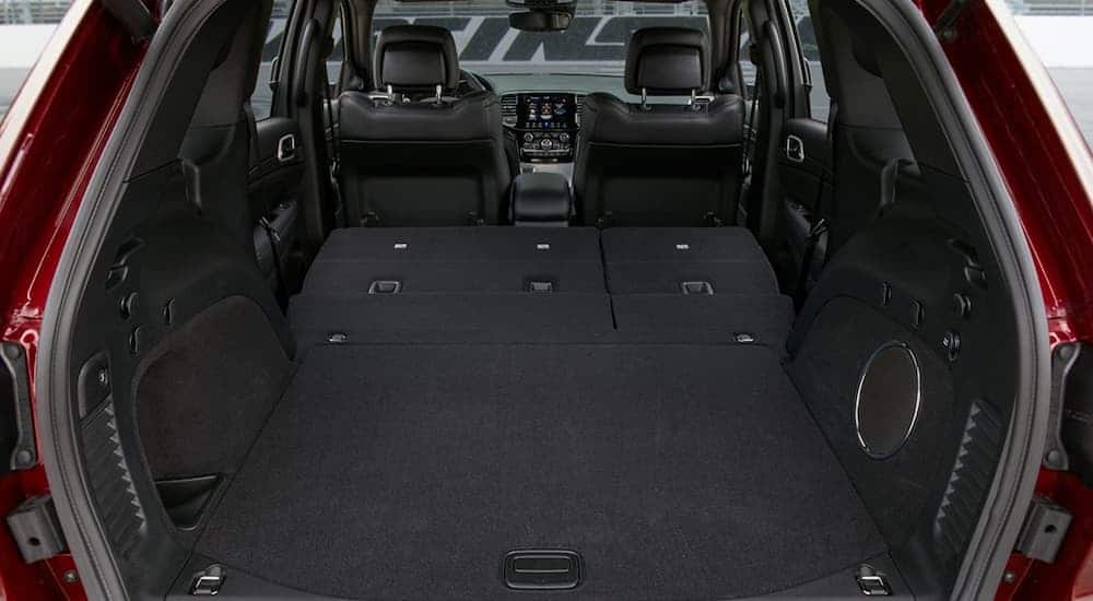 A rear to front view of the black leather interior of a 2020 Jeep Grand Cherokee is shown with the rear seats down.
