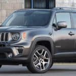 A grey 2020 Jeep Renegade is parked in front of a brick building.
