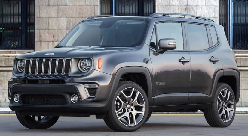 A grey 2020 Jeep Renegade is parked in front of a brick building.