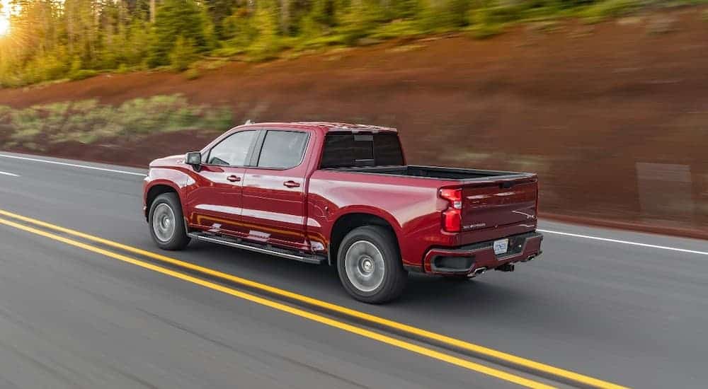 A red 2020 Chevy Silverado is driving past a red dirt hill.