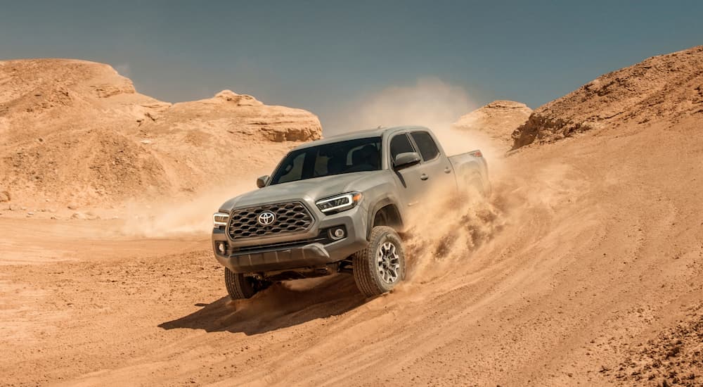 A gray 2020 Toyota Tacoma is driving down a sandy hill in the desert.