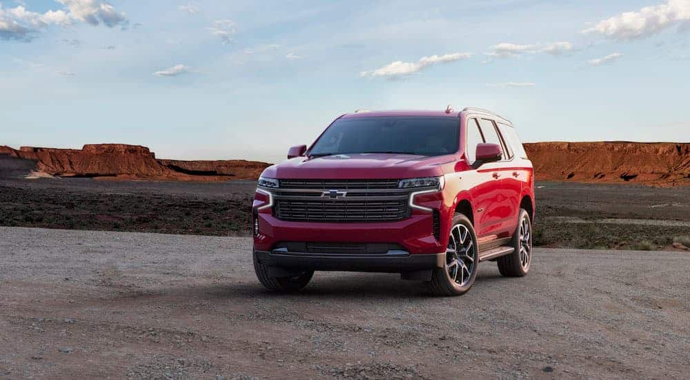 A red 2021 Chevy Tahoe RST, which has horsepower to make a statement within current auto news, is parked off road with mountains in the distance