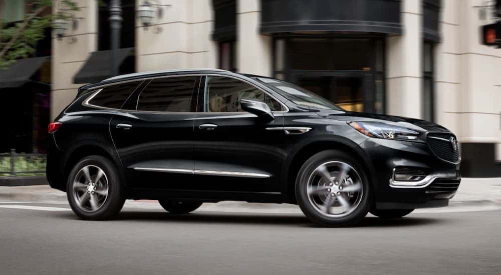 A black 2020 Buick Enclave is driving on a city street.