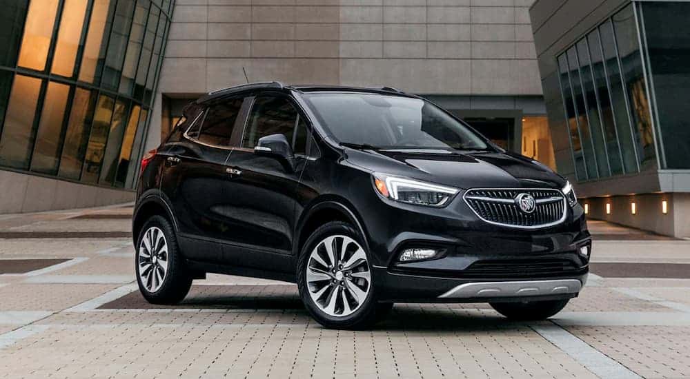 A black 2020 Buick Encore, popular among Buick SUVs, is parked in front of a building with lots of windows.