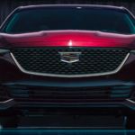 A close up of the front grille of a red 2020 Cadillac model is shown in a dark room.