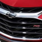 A close up view of the Chevy logo on a red Chevy Sonic is shown.