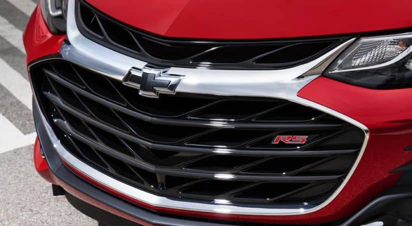 A close up view of the Chevy logo on a red Chevy Sonic is shown.